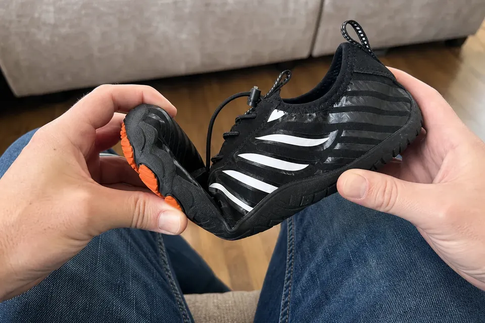 Black Grounded-style shoe bent by hand to show sole flexibility